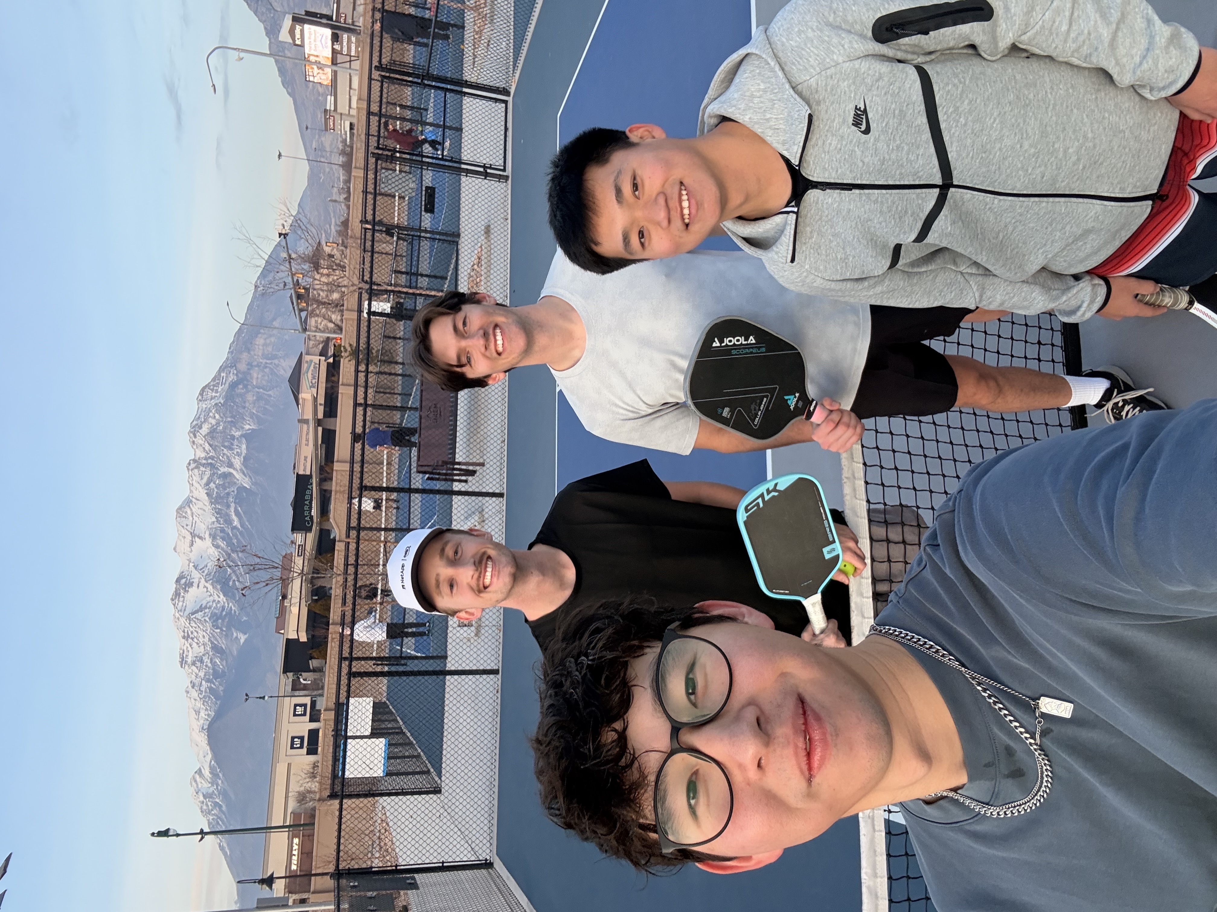 Friends playing pickleball outdoors with Utah mountains in the background